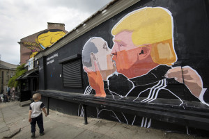 A child walks past a graffiti depicting Russian President Vladimir Putin, left, and Republican presidential candidate Donald Trump, on the walls of a bar in the old town in Vilnius, Lithuania, Saturday, May 14, 2016. (AP Photo/Mindaugas Kulbis)