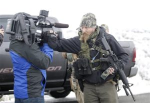 A man standing guard pushes a videographer aside after members of the "3% of Idaho" group along with several other organizations arrived at the Malheur National Wildlife Refuge near Burns, Ore., on Saturday, Jan. 9, 2016. A small, armed group has been occupying the remote national wildlife refuge in Oregon for a week to protest federal land use policies. (AP Photo/Rick Bowmer)