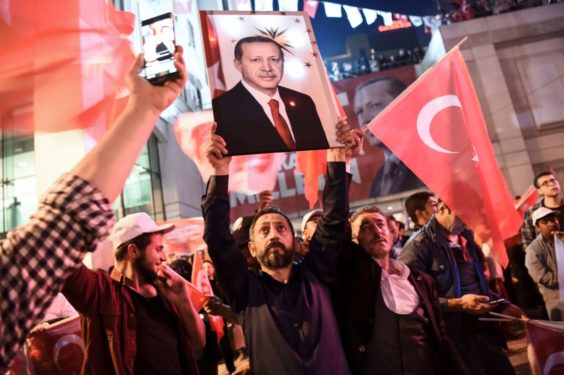 A supporter of the "yes" brandishes a picture of Turkish president Recep Tayyip Erdogan among other supporters waving Turkish national flags during a rally near the headquarters of the conservative Justice and Development Party (AKP) on April 16, 2017 in Istanbul after the initial results of a nationwide referendum that will determine Turkey's future destiny. The "Yes" campaign to give Turkish President expanded powers was just ahead in a tightly-contested referendum but the 'No' was closing the gap, according to initial results. / AFP PHOTO / OZAN KOSE (Photo credit should read OZAN KOSE/AFP/Getty Images)